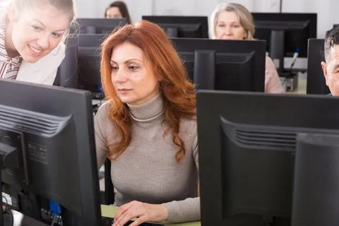 Young female teacher explaining computer skills to mature woman Stock-Fotos