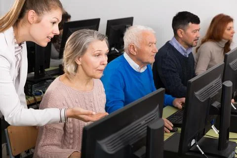 Young female teacher explaining computer skills to mature woman 写真素材