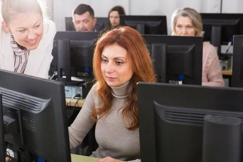 Young female teacher explaining computer skills to mature woman 写真素材