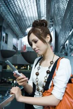 Young female text messaging on cell phone in shopping mall Stock Photos