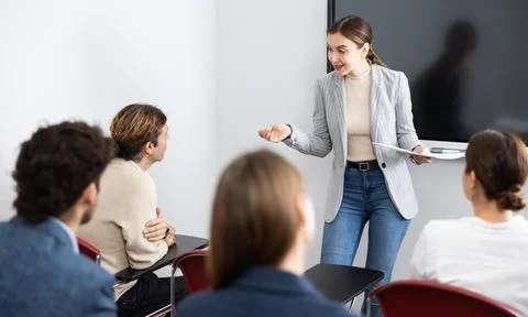 Young female tutor teaching students in college classroom Stock Photos