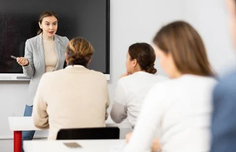 Young female tutor teaching students in college classroom Stock Photos