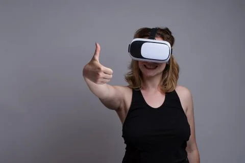 Young female using a 3D VR wearable is displaying a happy face and thumbs up Stock Photos