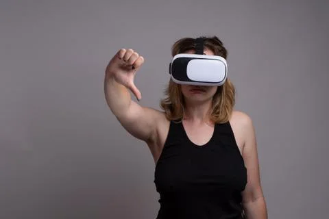 Young female using a 3D VR wearable is displaying a happy face and thumbs down Stock Photos