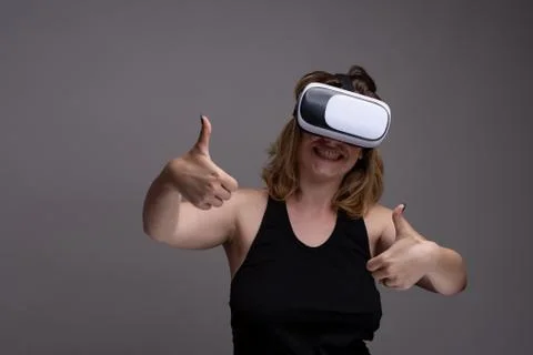 Young female using a 3D VR wearable is displaying a happy face and thumbs up Stock Photos