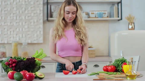 Young female using a knife to slice fresh tomatoes on a cutting board. Woman Stock Footage 244830618
