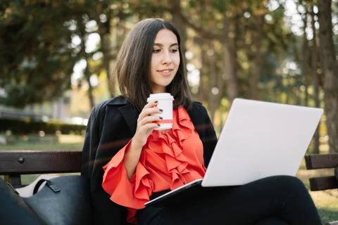 Young female using laptop while sitting on a bench Stock Photos