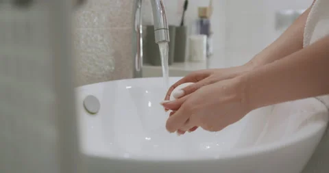 Young female using soap while washing hands under water tap. Close up of hands Stock Footage 147506935