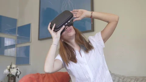 Young female wearing VR headset and experiencing virtual reality Stock Footage 80942648