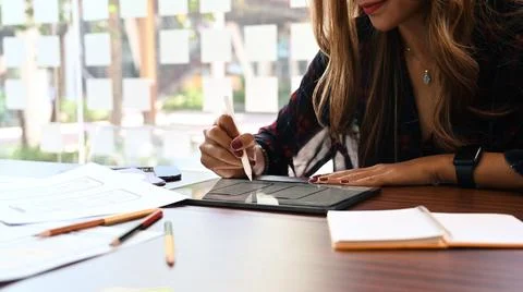 Young female web developer holding stylus pen and working on digital tablet at 写真素材