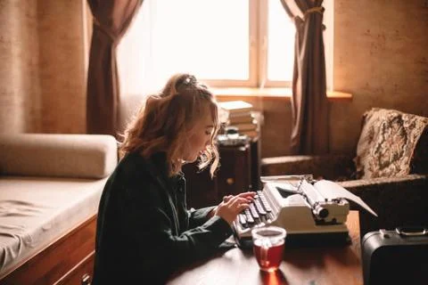 Young female writer using typewriter at home Stock Photos