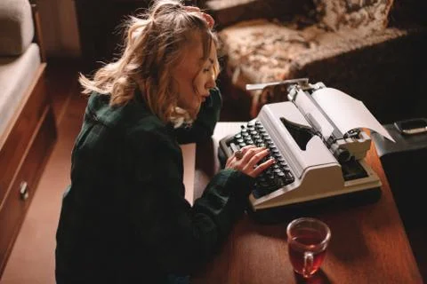 Young female writer using typewriter at home Stock Photos