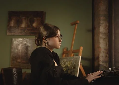 Young female writer writes a novel on a printing machine in an art studio Foto stock