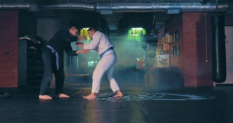 Young fighter in a kimono makes a capture of the enemy and inflicts a painful Stock Footage 121013057
