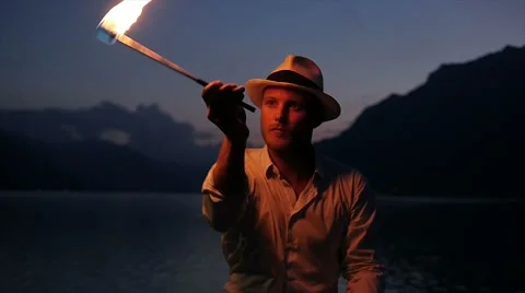 Young fire artist presenting show with torchlight flame at night sky Stock Footage 64802301