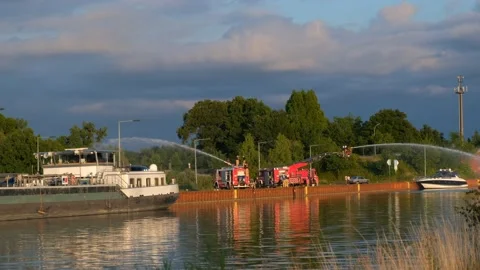 Young firefighters practice hosing down water on the banks of a water canal Stock Footage 221554012