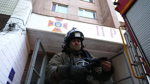 Young fireman putting protective gloves near against background of a big red car Stock-Footage 306321335