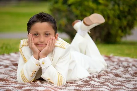 Young First Communion boy lying on a blanket over the grass 写真素材