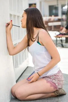 Young fit beautiful girl, artist, drawing letters on a white board. Stock Photos