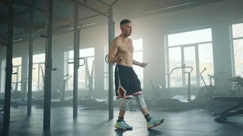 Young fit boxer performing different exercises jumping on rope in equipped gym Stock Footage 240249960