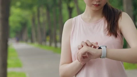 Young fit female runner checking time on her wrist watch before jogging, runn Stock Footage 247037822