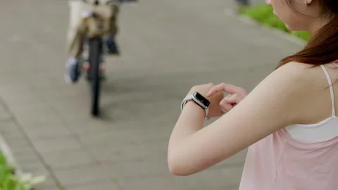 Young fit female runner checking time on her wrist watch before jogging, runn Stock Footage 247038017