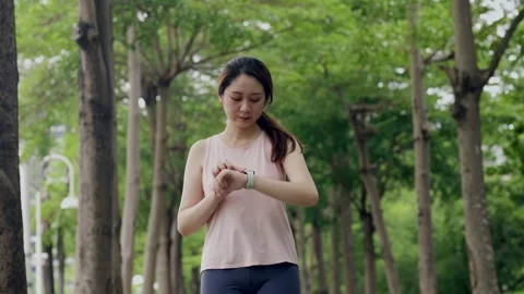 Young fit female runner checking time on her wrist watch before jogging, runn Stock Footage 247038078