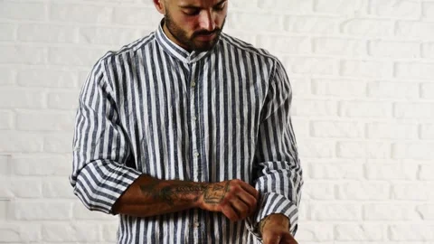 Young fit man buttoning up striped shirt 動画素材 181945376