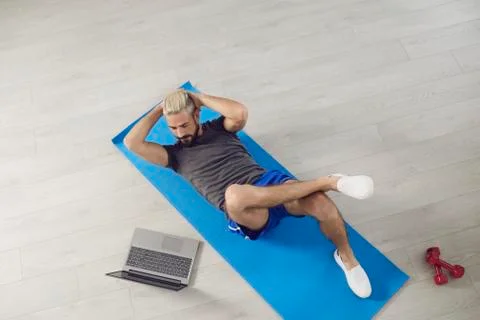 A young fit man does workout exercises on the abs while lying on the floor Stock Photos