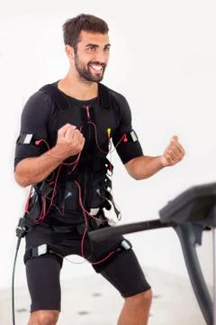 Young fit man exercise biceps curl on  electro muscular stimulation machine Stock Photos