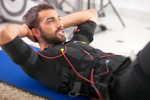 Young fit man exercise on  electro muscular stimulation machine Stock Photos
