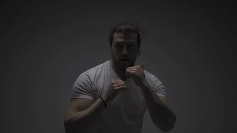 Young fit man fighting with camera in half light room Stock Footage 126723579