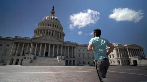 Young fit man jumping for joy in front of the US Capitol in Washington, DC in Stock Footage 128717843