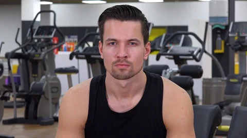 A young fit man looks at the camera in a gym - closeup 스톡 동영상 87929586
