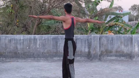Young Fit Man Performing Standing Spinal Twist Exercise on Rooftop Video stock 330390408