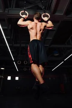 Young fit man pulling up on gymnastic rings. Stock Photos