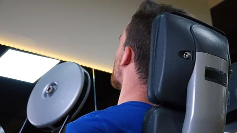 A young fit man sits down to a machine in a gym and starts training - closeup Stock-Footage 85853964