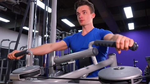 A young fit man trains on a machine in a gym - closeup Stock-Footage 85877905