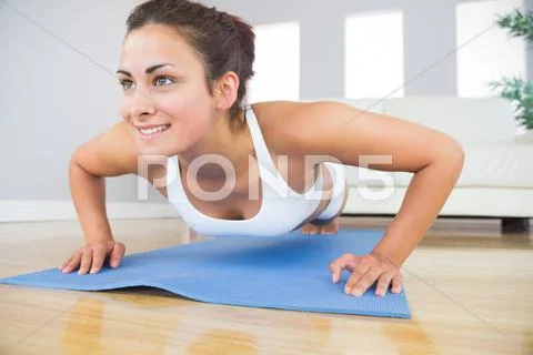 Young fit woman doing press ups on an exercise mat Stock Photos