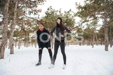 Young Fitness Couple Having Break After Running In Winter Forest