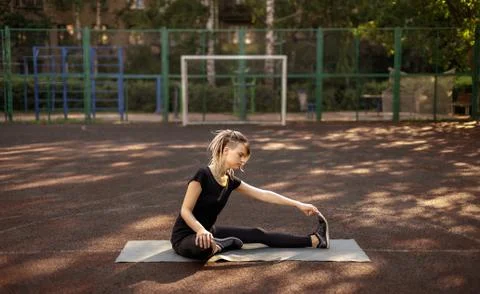 Young fitness girl doing stretching and yoga on a playground Stock Photos