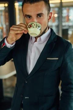 Young focused businessman drinking coffee in cafe. Indoor photo. Stock Photos