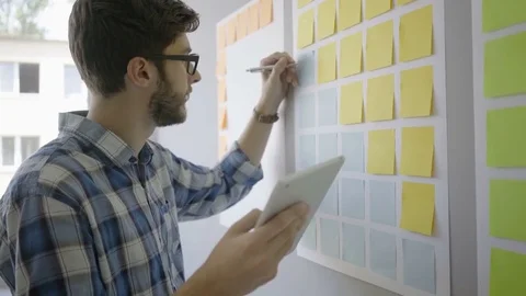 Young focused man planning with tablet and sticky notes Stock Footage 79795450