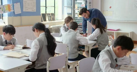 Young foreign teacher helping students in class,4K Stock Footage 120897501