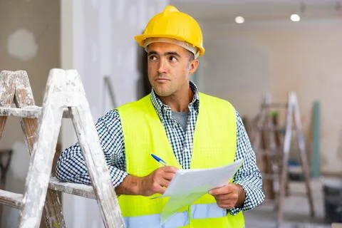 Young foreman checks the completed construction work and signs the documents Stock Photos