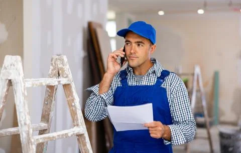 Young foreman with documents in his hands is talking on a mobile phone Stock Photos