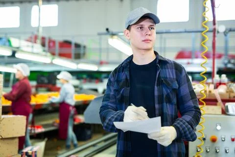 Young foreman with papers controlling work on tangerines sorting line Stock Photos