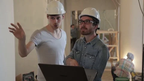 Young foremens talking looking at laptop standing indoors. Stock Footage 77519657