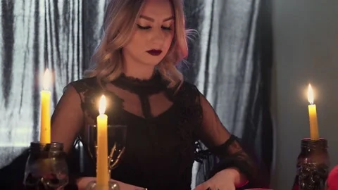 Young fortune teller at the table by candlelight reads the future on the cards Stock Footage 143508549
