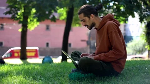 Young freelance business man using modern laptop in sunny green park searching 스톡 동영상 138881683